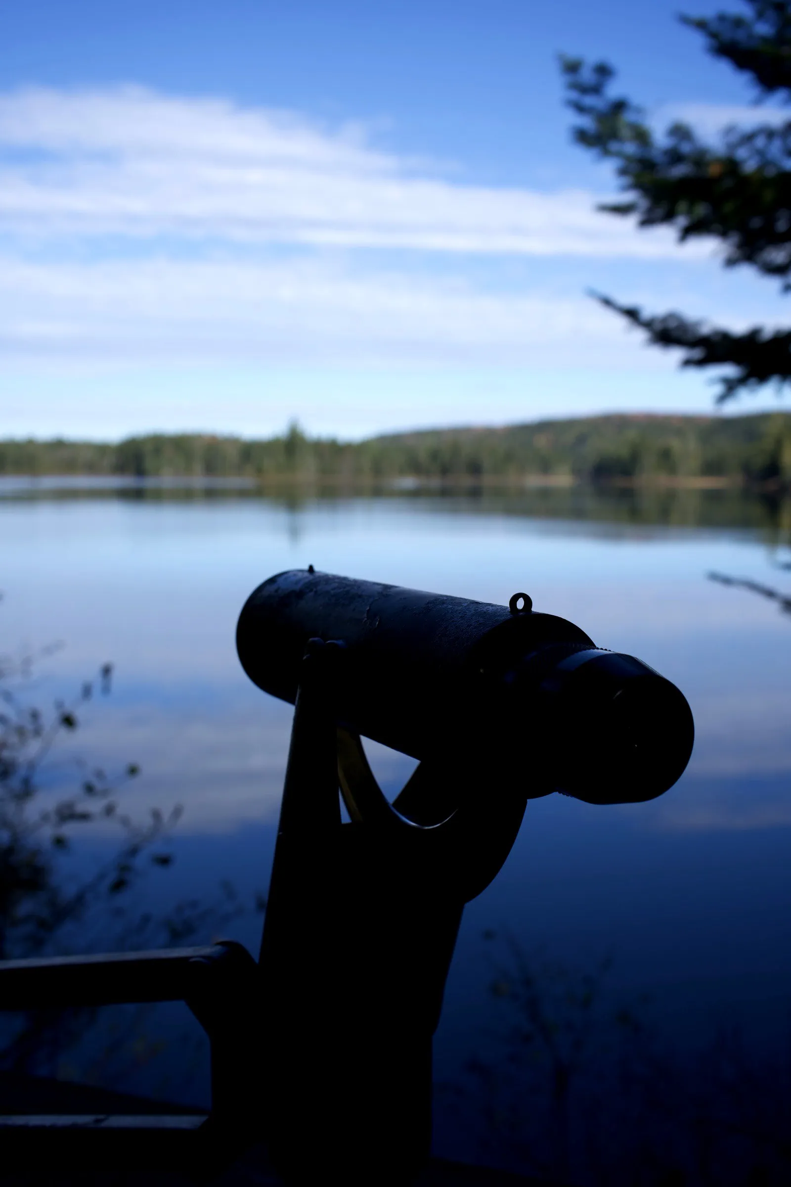 A coin-operated viewer facing a calm lake in Québec